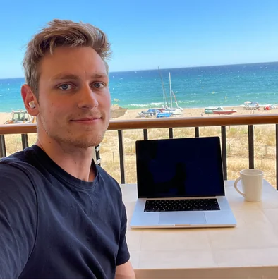 Jan with his laptop at a table overlooking the beach and sea