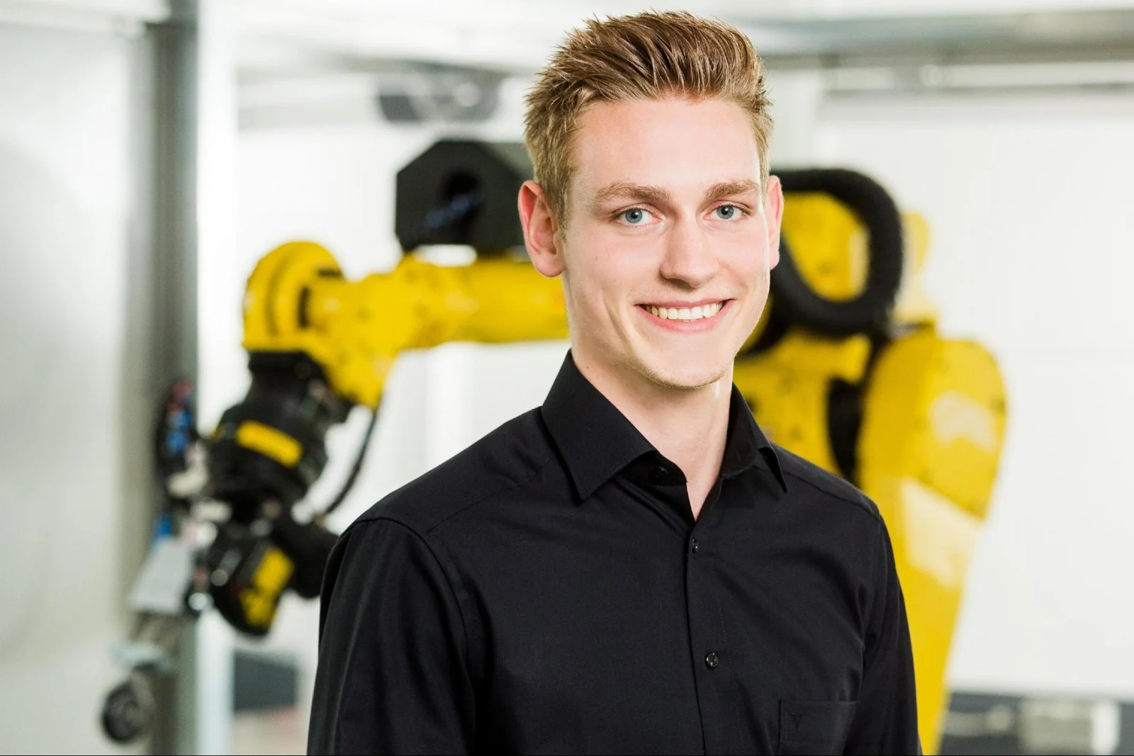 Jan during his engineering years, standing beside an industrial robot